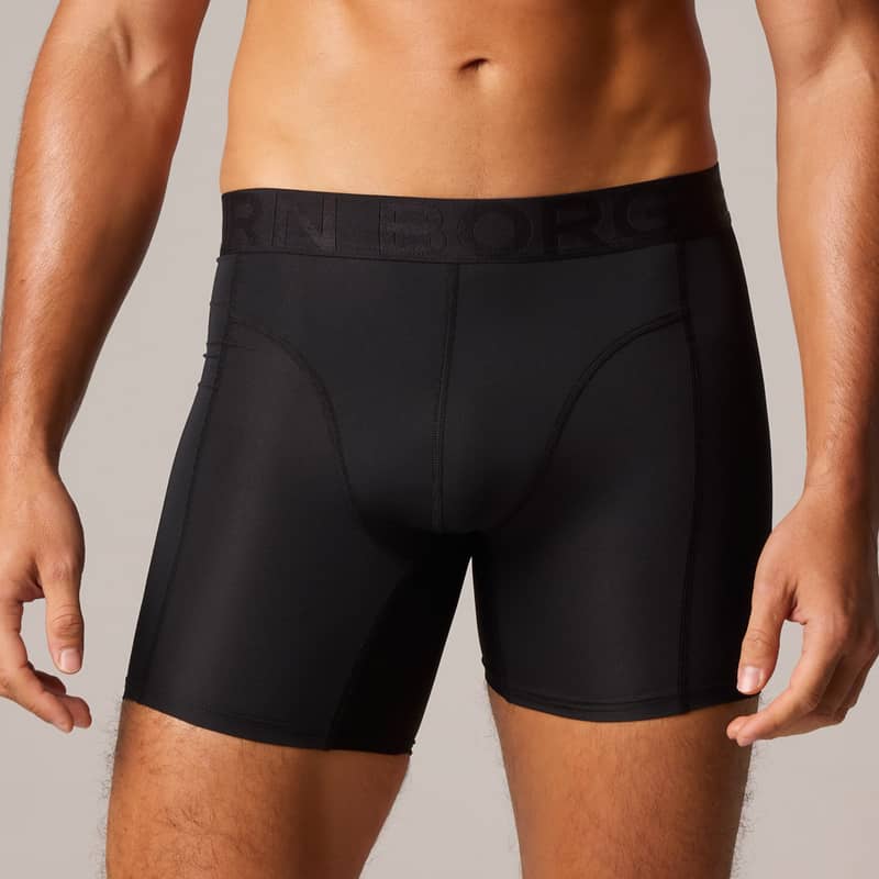 Man wearing black fitted boxer briefs with Björn Borg logo on waistband, showing a partial view of his torso and legs against a neutral background.