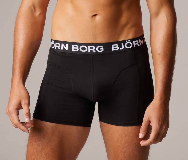 Man wearing black Björn Borg boxer briefs, with logo waistband, against a gray background.