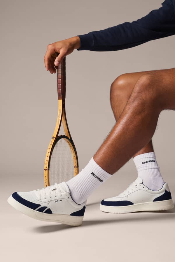 White and navy court sneakers styled with a vintage tennis racket.