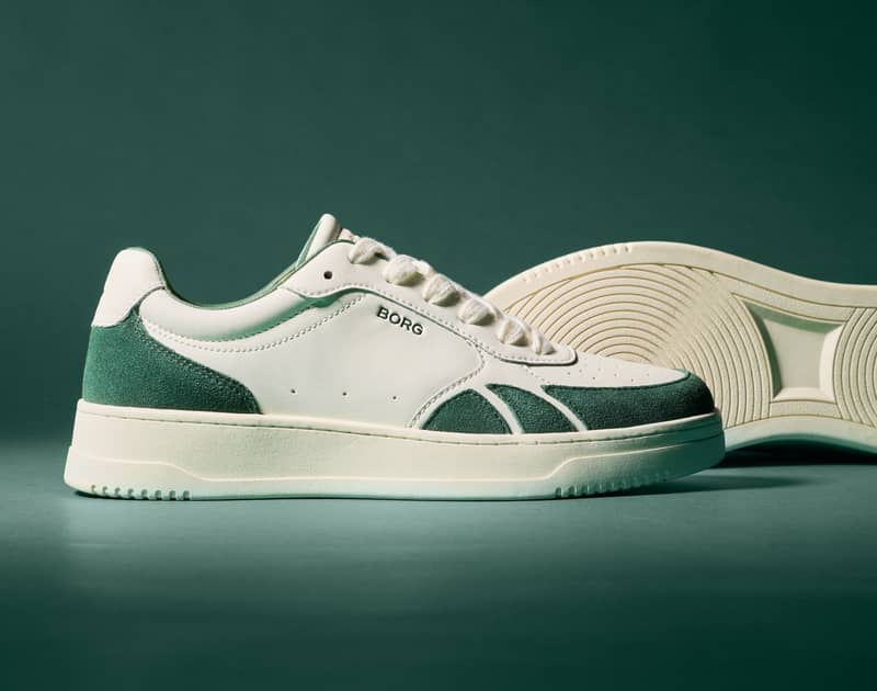 White and green sneaker with "BORG" branding on the side, displayed with a textured sole against a green background.