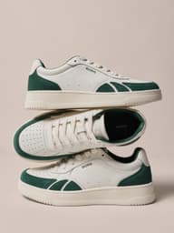 White and green court sneakers stacked in a product display.