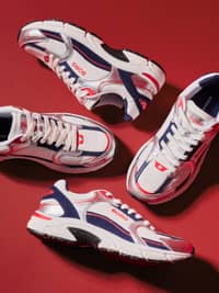 White, navy and red performance sneakers arranged on red background.