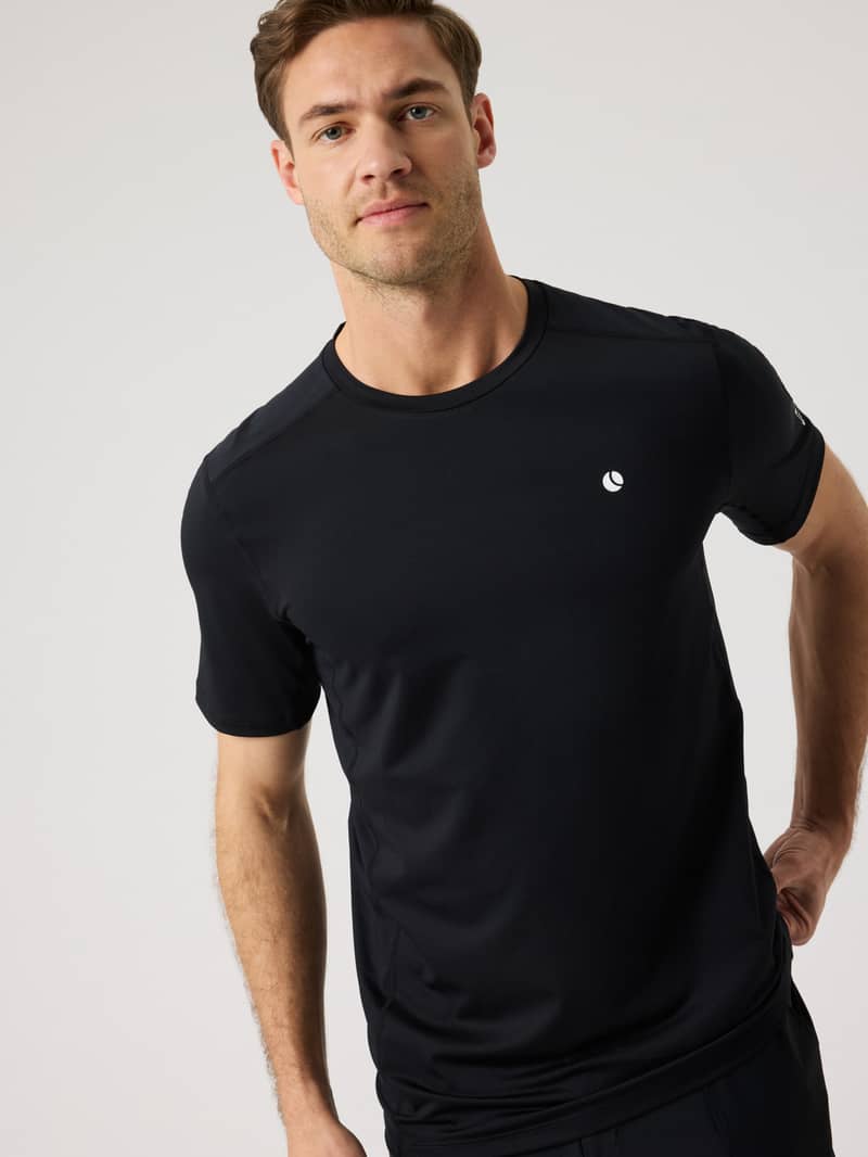 Man in a black athletic t-shirt with a small logo near the chest, standing against a plain background.