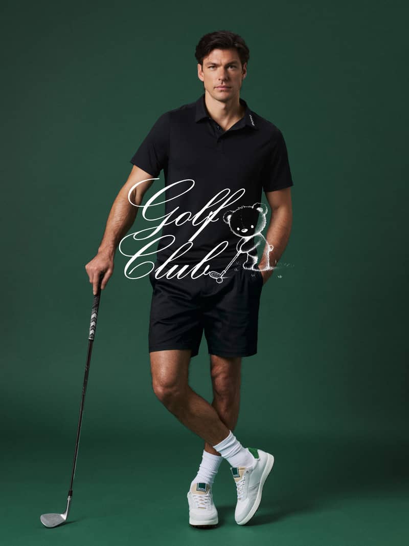 Man in a black polo and shorts holds a golf club against a dark green background. White text overlay reads "Golf Club" with a bear graphic.