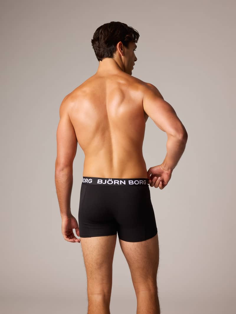 A man standing with his back to the camera, wearing black Björn Borg boxer briefs against a neutral background.