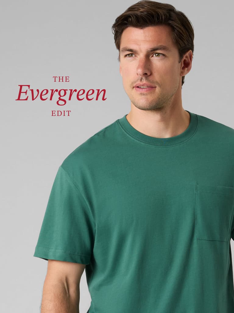 Man in a green T-shirt with a pocket stands against a gray background. The text reads "The Evergreen Edit."
