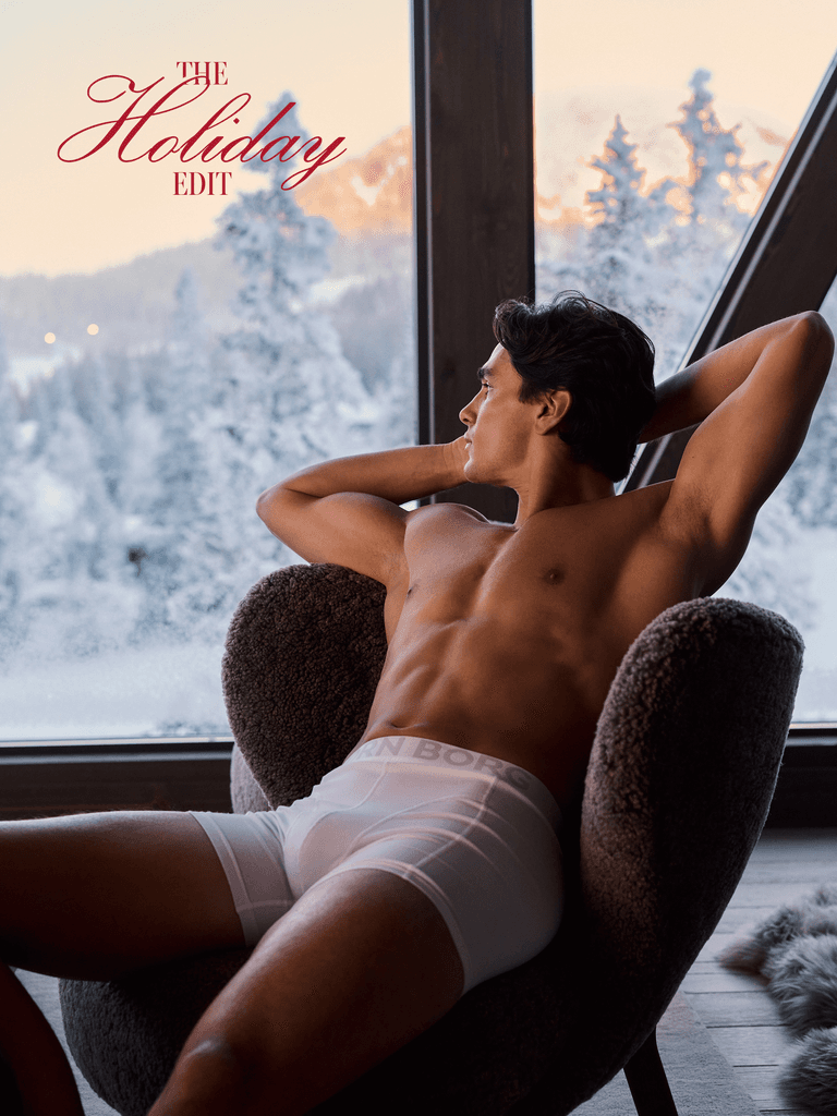 Man wearing white boxers while seated beside a snowy window