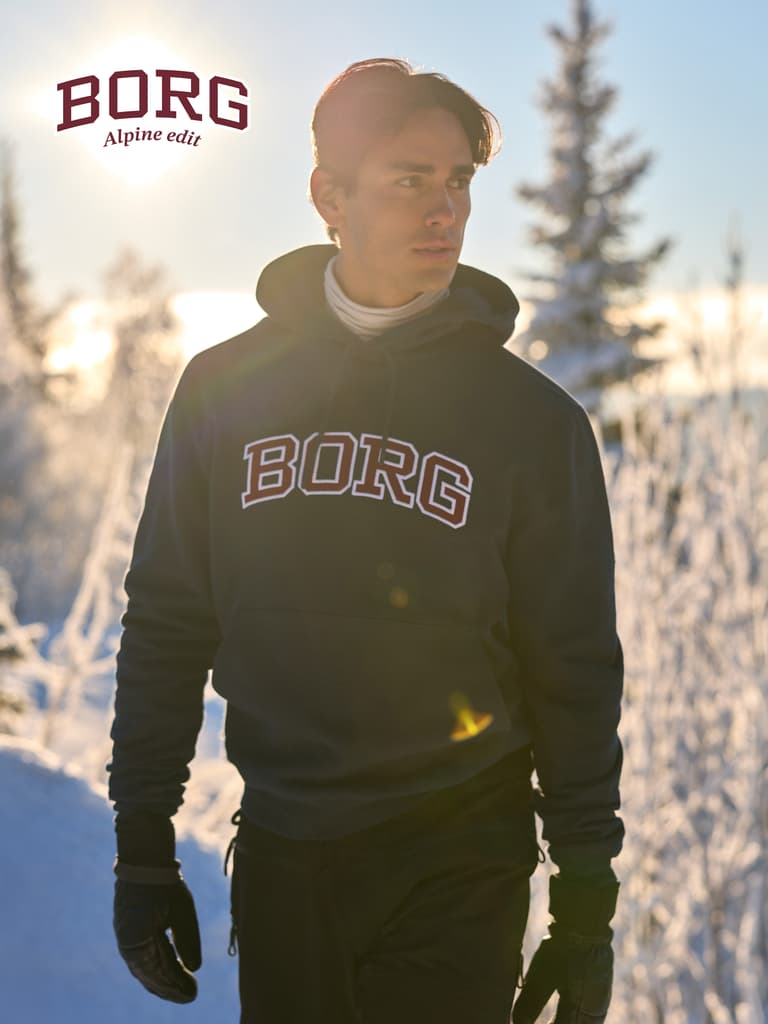 Man wearing a dark BORG hoodie over a light base layer in a snowy setting