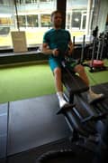 A man dowing rowing back exercise on the machine at the gym. He is wearing a blue-green set with Björn Borg t-shirt and shorts plus white Björn Borg shoes.