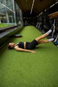 Woman doing flutter kicks exercise at the gym, wearing a black sports bra, black ribbed bike shorts and black sneakers from Björn Borg