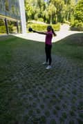 A blond woman outdoors in a pink Borg T-shirt, black Borg Running Tights and white Björn Borg sneakers, doing kettlebell swings