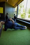 A blond woman doing a side plank at the gym. She is wearing a blue sports bra and matching Sleek Tights from Björn Borg