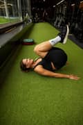 Woman doing a reverse crunch exercise at the gym. She is wearing a black sports bra, black ribbed bike shorts and black sneakers from Björn Borg