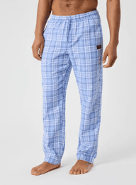 Man wearing light blue plaid pajama pants with an elastic waistband, standing barefoot against a plain background.