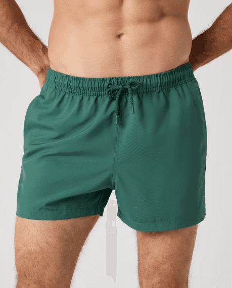 A person wearing green swim trunks with a drawstring, showcasing a relaxed fit, against a plain background.