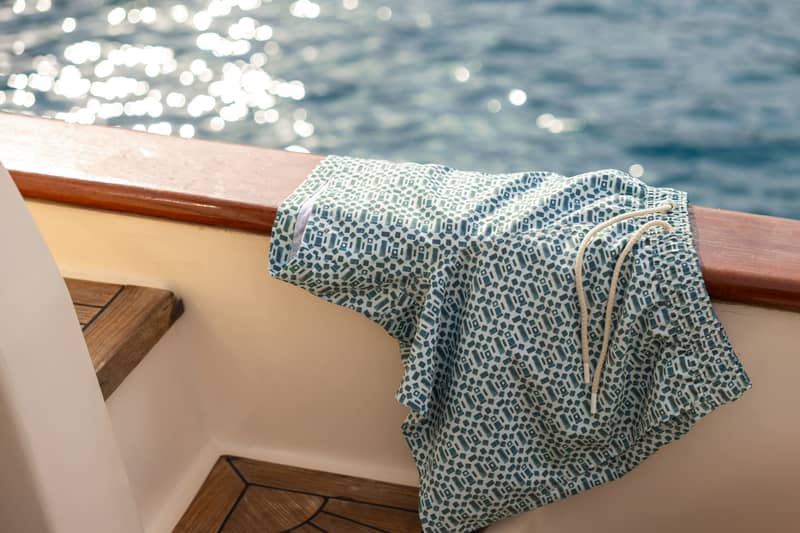 Patterned Björn Borg swim shorts placed on boat bench by water
