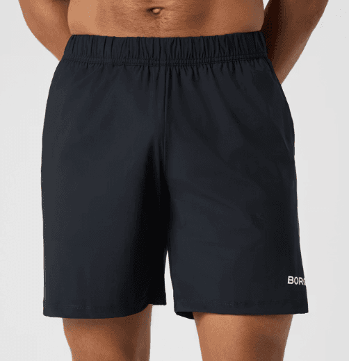 A person wearing black athletic shorts with an elastic waistband and a small logo on the hem.