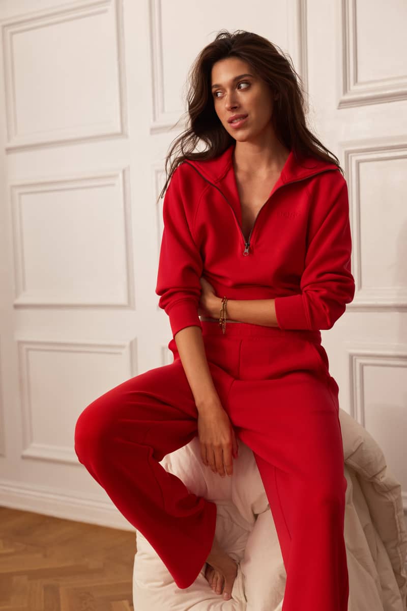 Woman wearing a red half-zip sweatshirt and matching wide-leg pants.