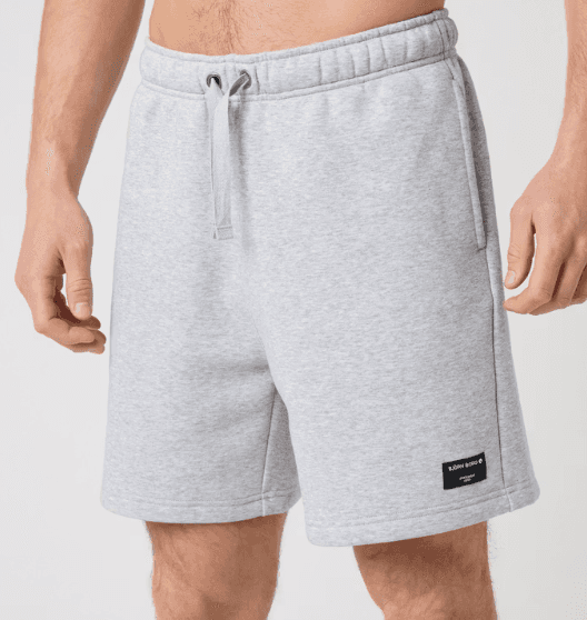 A person wearing light gray drawstring shorts, featuring side pockets and a small black label near the hem.