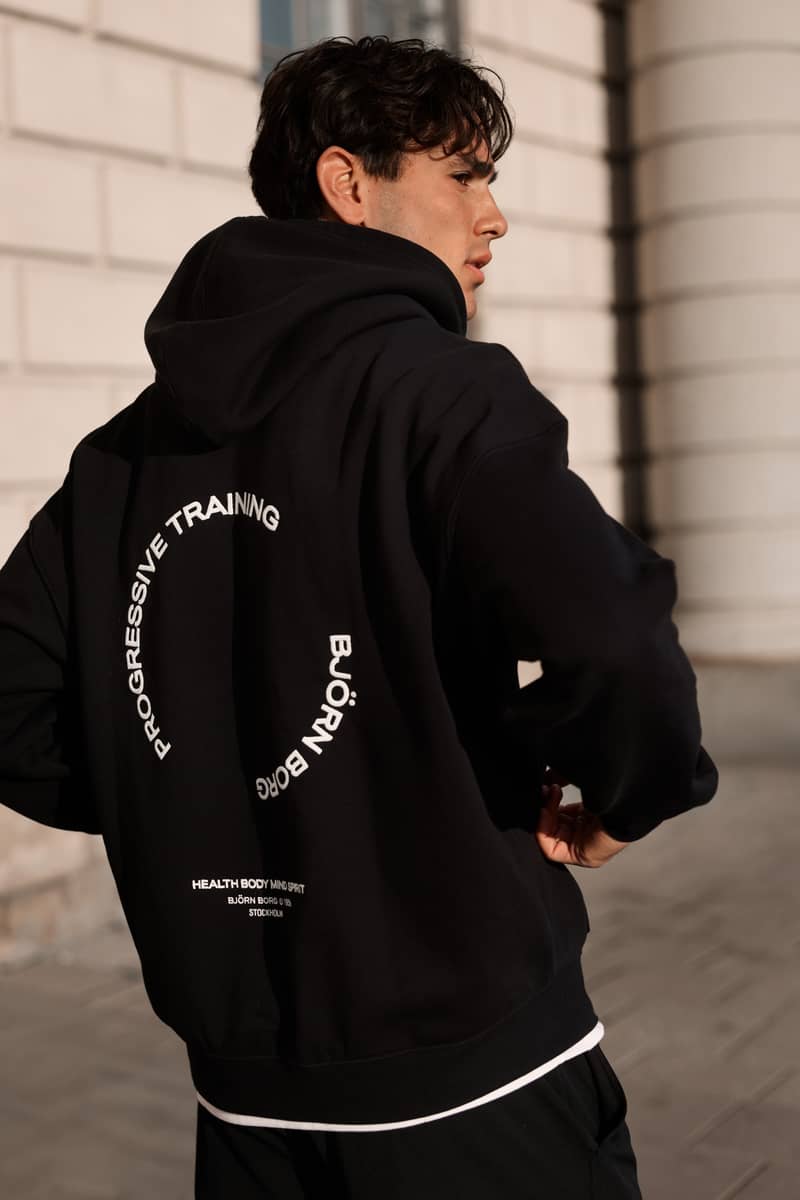 Man wearing a black hoodie with Progressive Training back print
