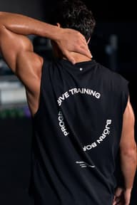 Back view of a man wearing a black sleeveless training top with a Progressive Training graphic print.