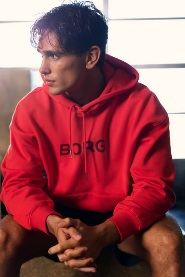 Man wearing a red hoodie seated in a gym environment