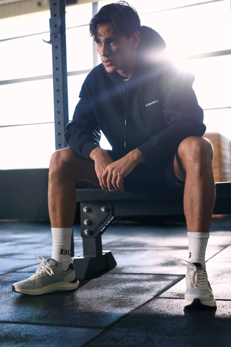 Man wearing a black hoodie seated on a gym bench