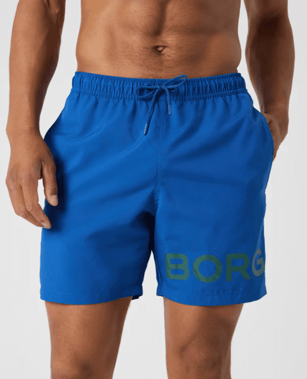 Man wearing blue swim shorts with "BORG" text, featuring an elastic waistband and drawstring.