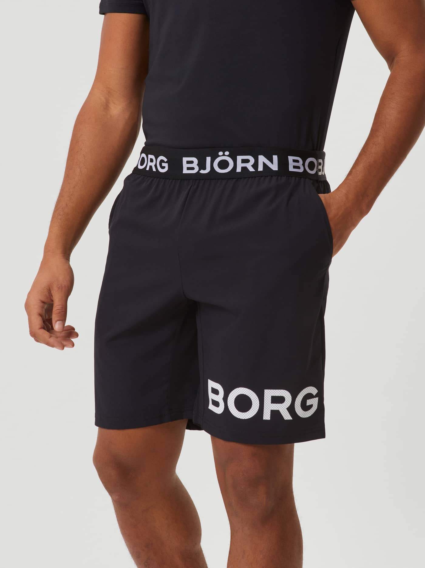 Front view of a man wearing Black Beauty (Black) Borg Shorts for training, featuring a large white logo on the leg. - Image 2
