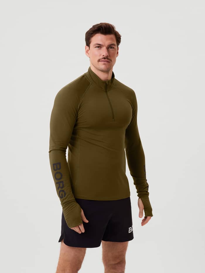 Vooraanzicht van een man in de Borg Midlayer Half Zip in Dark Olive (Groen) met zwarte logo's voor training. - Image 3