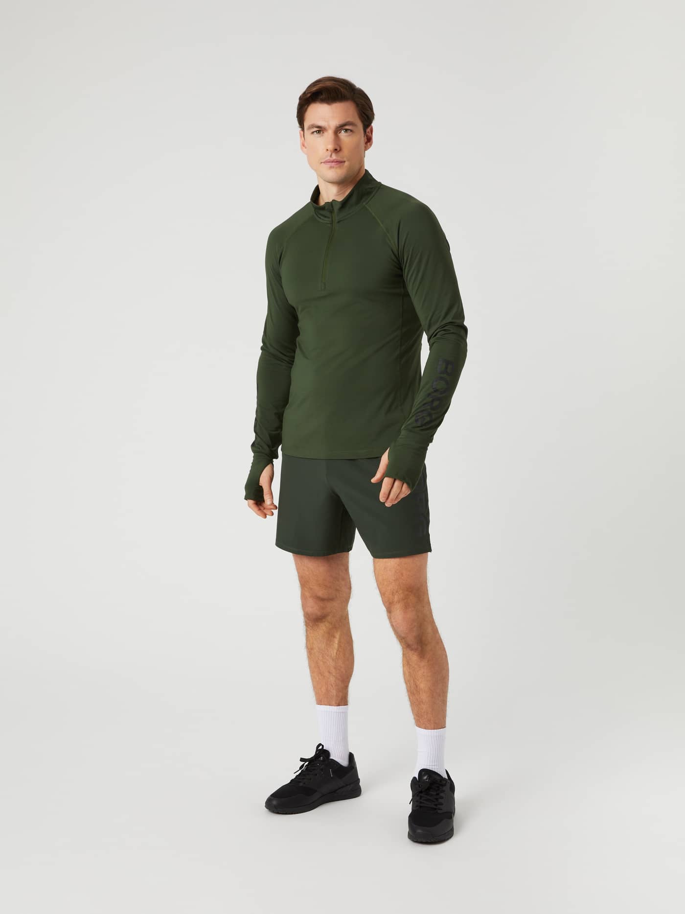 Vooraanzicht van een man in de performance Borg Midlayer Half Zip in Duffel Bag (Groen) met zwart logo voor training. - Image 3