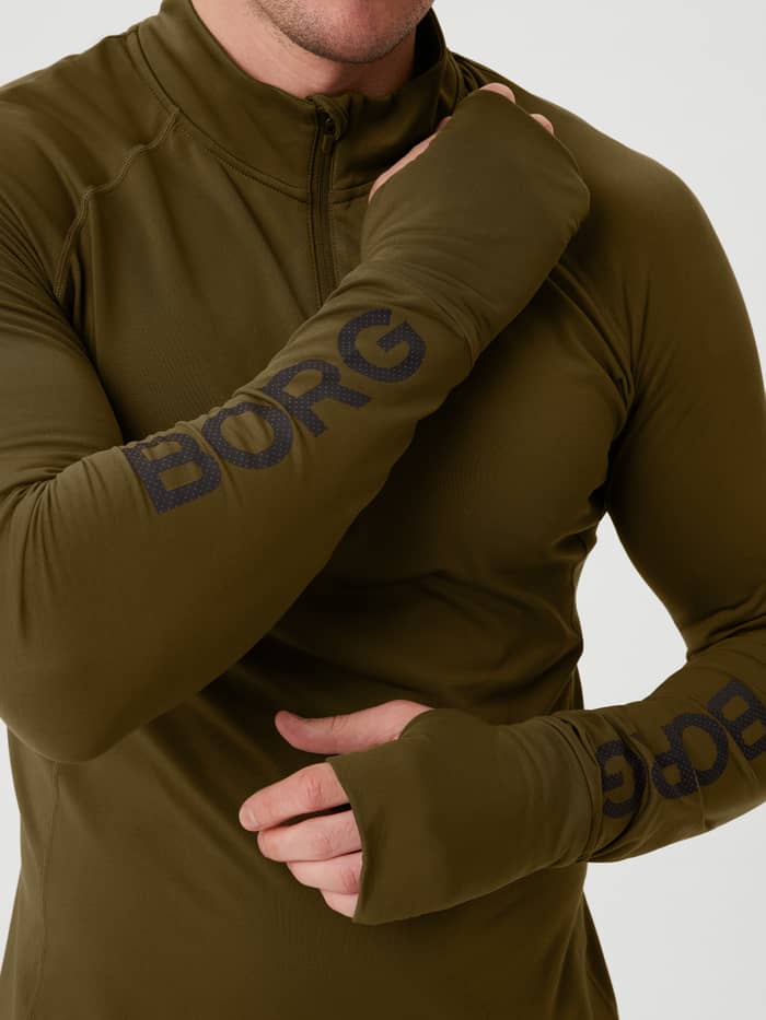 Nahaufnahme des Borg Midlayer Half Zip in Dark Olive (Grün) für das Training mit Daumenlochöffnungen und schwarzen Logos.