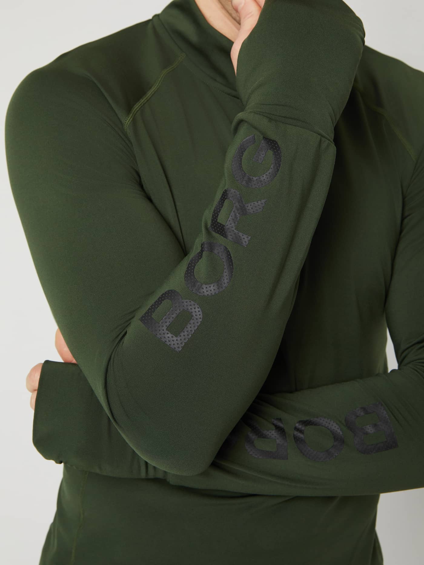 Detailopname van de Borg Midlayer Half Zip in Duffel Bag (Groen) met zwarte mouwlogo's en duimgaten voor training. - Image 4