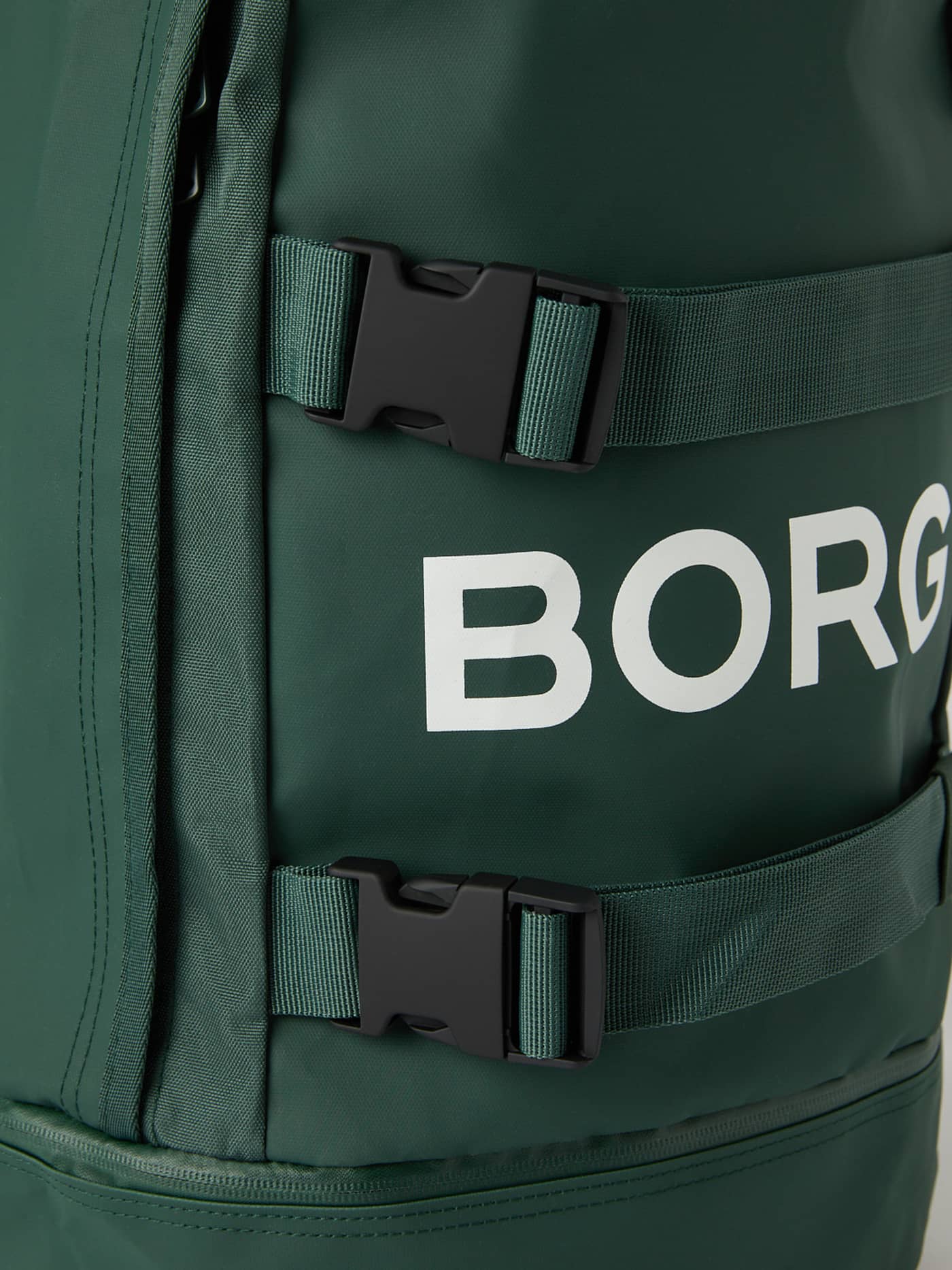 Detaljert nærbilde av Sycamore (Grønn) Borg Duffle Backpack 28L til trening med hvit logo og svarte spenner. - Image 6