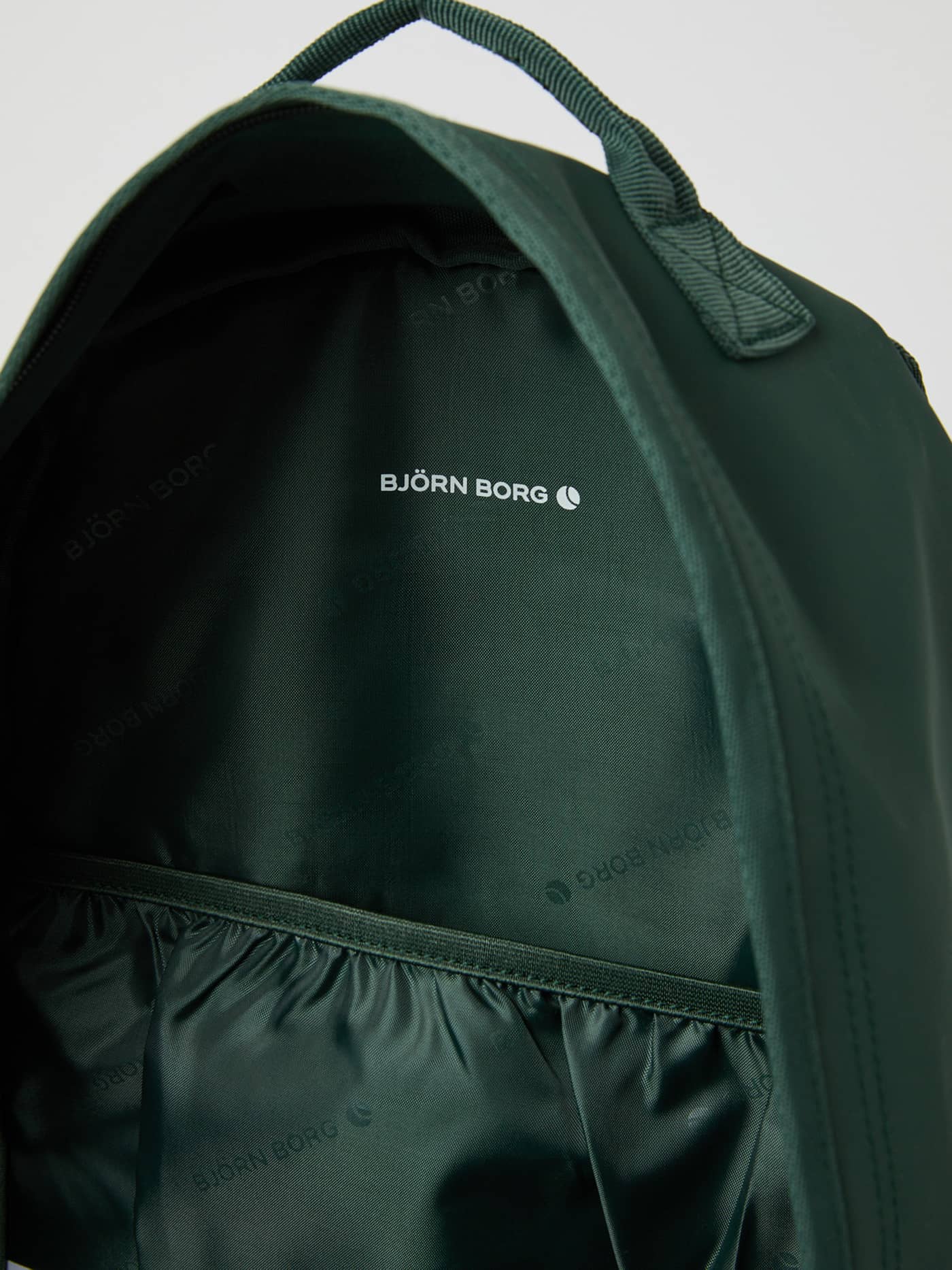 Borg Duffle Backpack 28L i Sycamore (Grønn) sett innenfra med hvit logo og mønstret fôr. - Image 4
