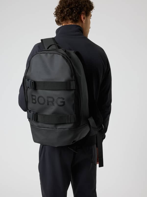 Rear view of a man wearing the black Borg Duffle Backpack 28L with a durable coated material and tonal logo for training.