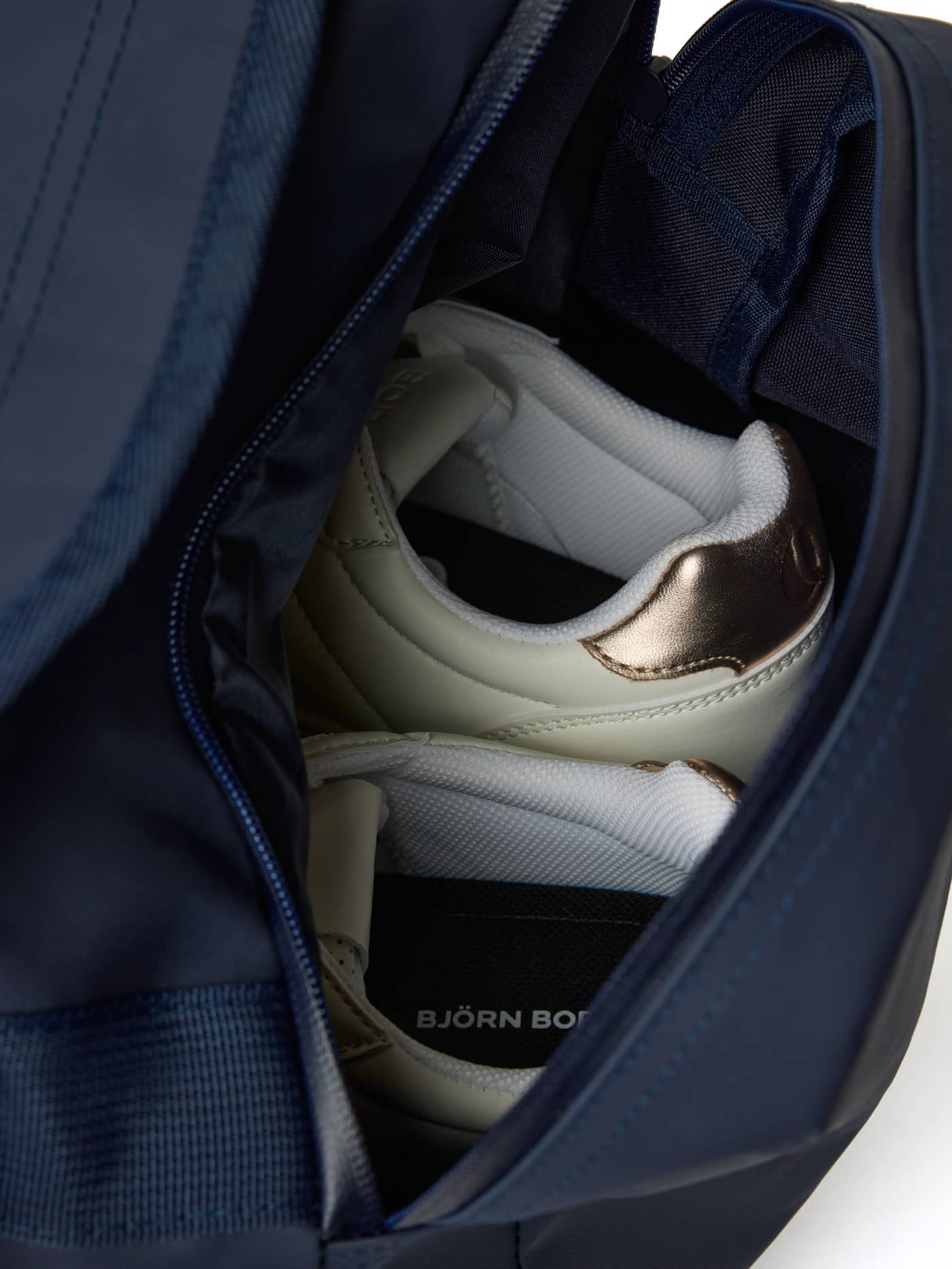 Close-up of the internal wet pocket in the Borg Duffle Bag 35L in Night sky (Navy), containing a pair of shoes. - Image 4