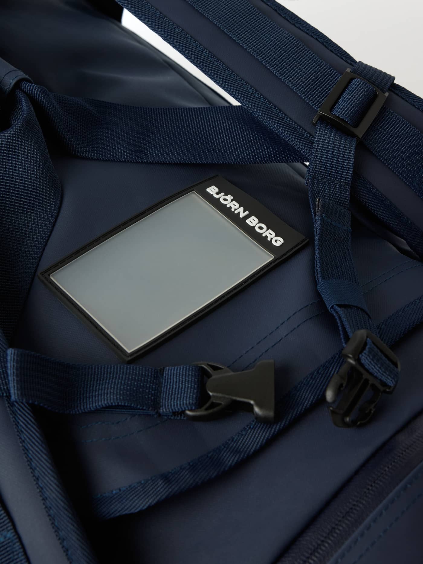 Detailed close-up of the address tag and straps on the coated Borg Duffle Bag 35L in Night Sky (Navy). - Image 7