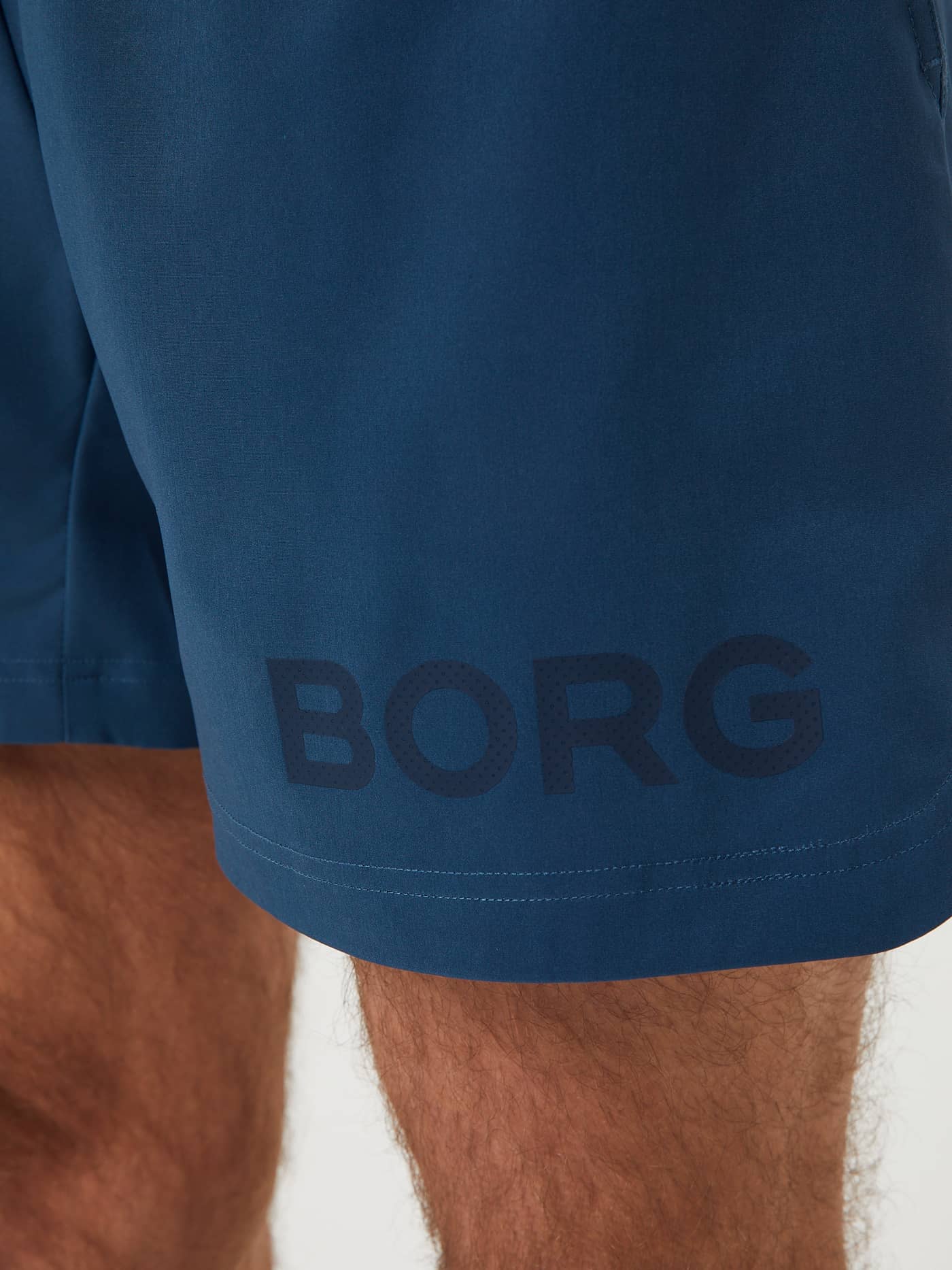 Detailed close-up of the Blue Wing Teal (Blue) Borg Short Shorts, technical training shorts with a dark blue tonal logo. - Image 4