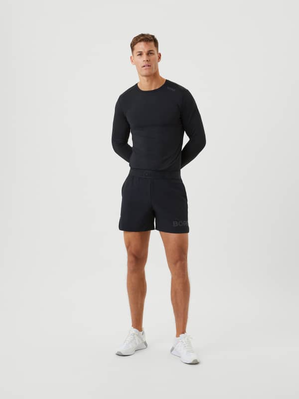 Full-body front view of a man wearing the Björn Borg Short Shorts in Black Tonal Logo (Black) for training.