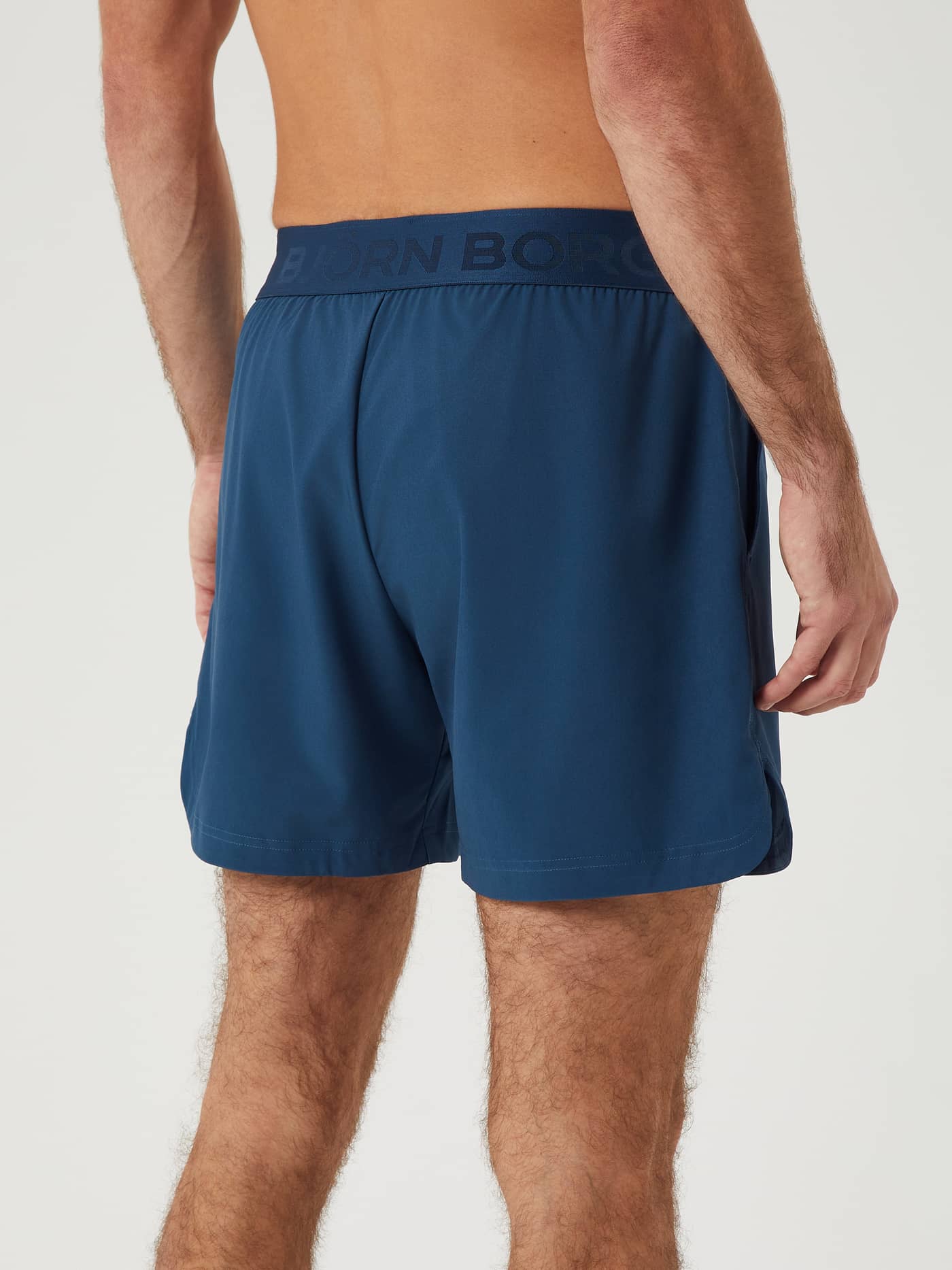 Back view of a man wearing the training Borg Short Shorts in Blue Wing Teal (Blue) with a signature branded waistband. - Image 3