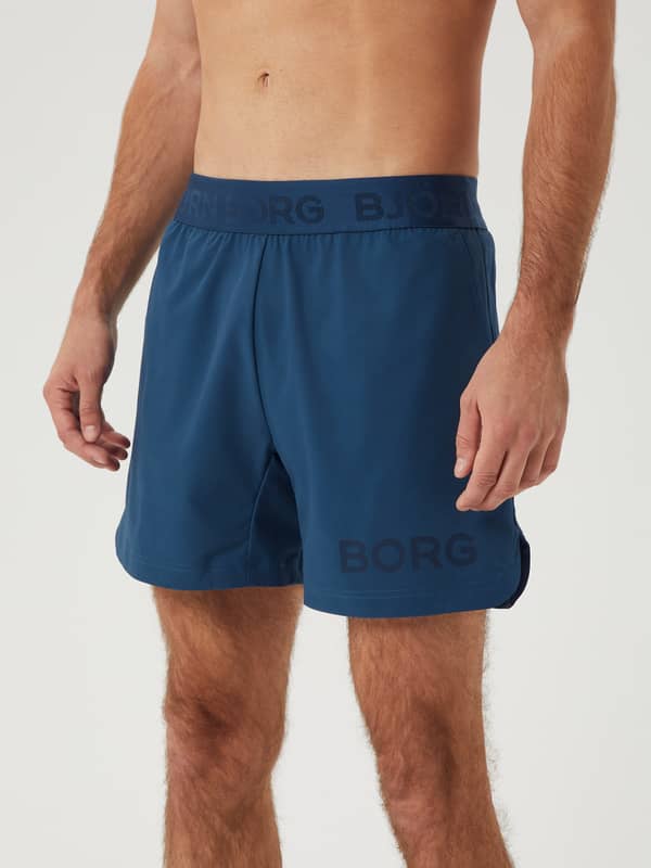 Front view of the Borg Short Shorts in Blue Wing Teal (Blue) for training, featuring a dark blue logo and side slits.