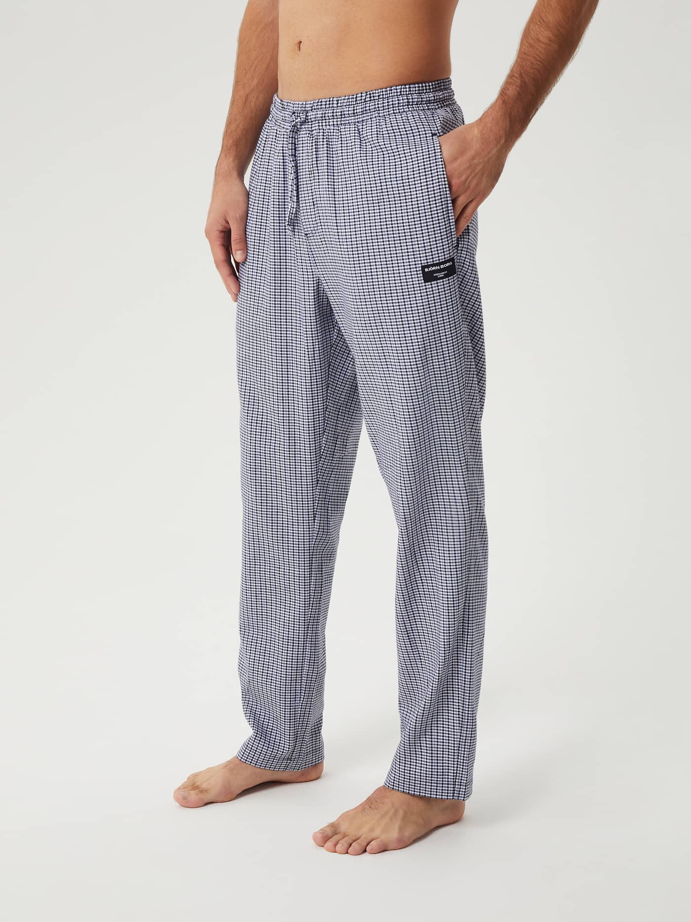 Side view of a man wearing the Björn Borg Core Flannel Pyjama Pants in a blue and white mini check pattern. - Image 2