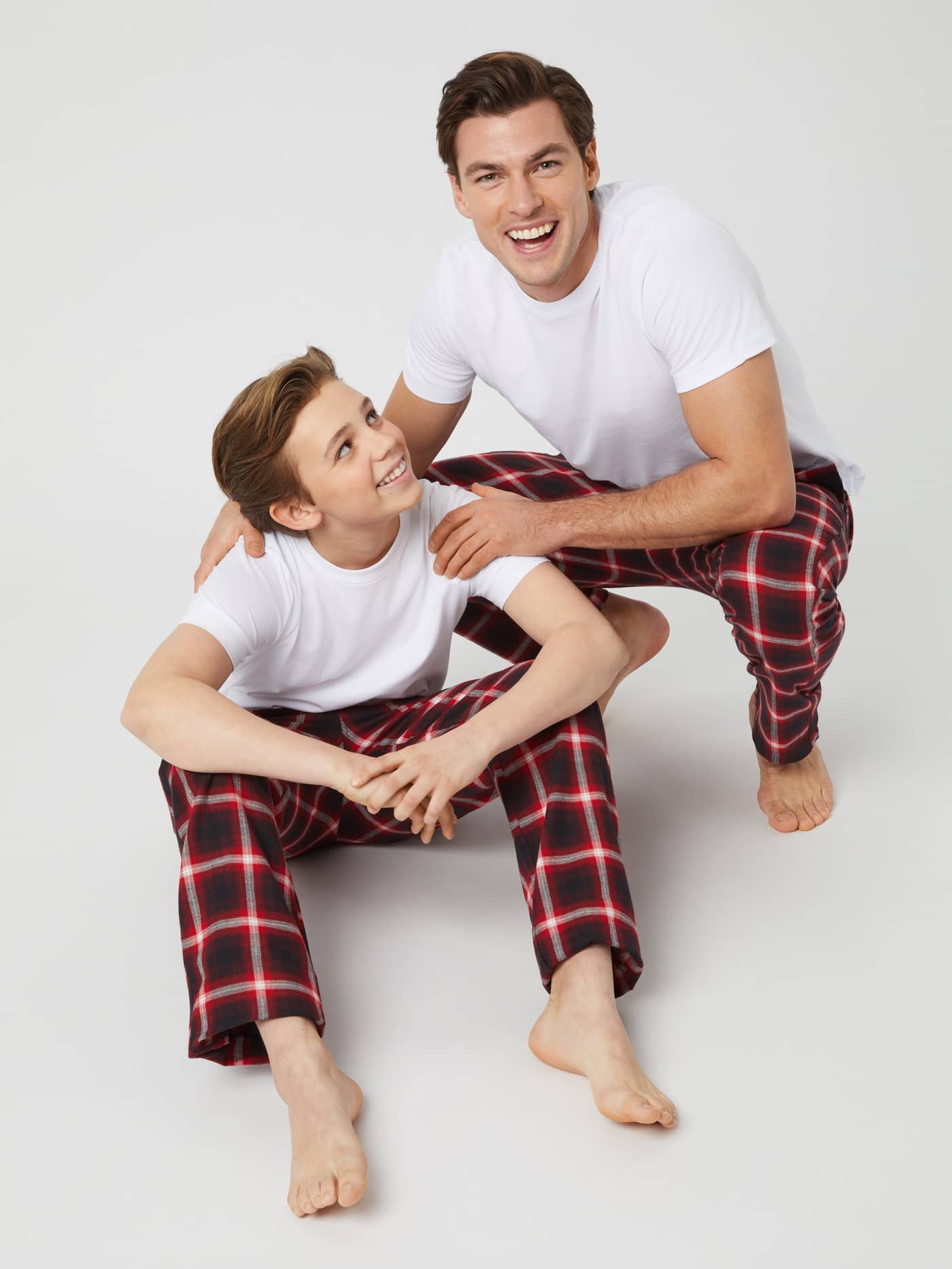 Matchande rutiga Core Flannel Pyjama Pants i Lumber Check (Röd) på en leende man och ett barn i mjuk flanell. - Image 3