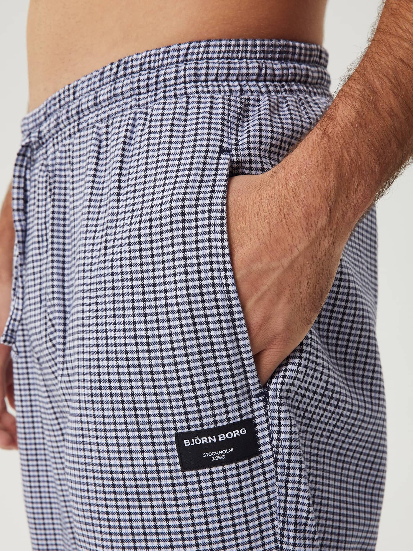 Close-up of a man wearing Björn Borg Core Flannel Pyjama Pants in a blue mini check pattern, with his hand in the pocket. - Image 4