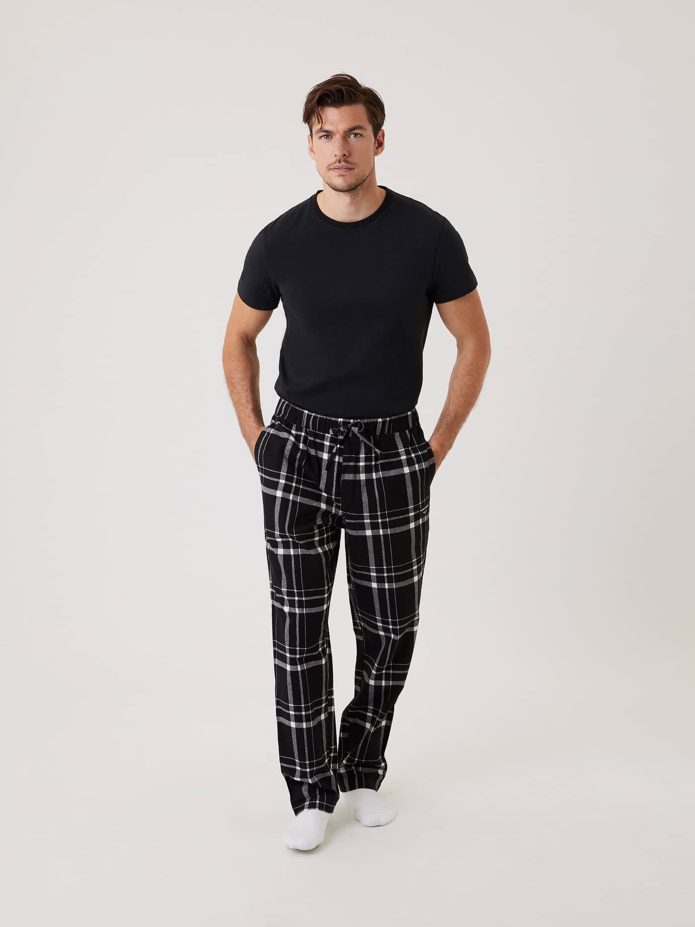 Full-length front view of a male model wearing the Björn Borg Core Flannel Pyjama Pants in a black and white plaid pattern. - Image 1