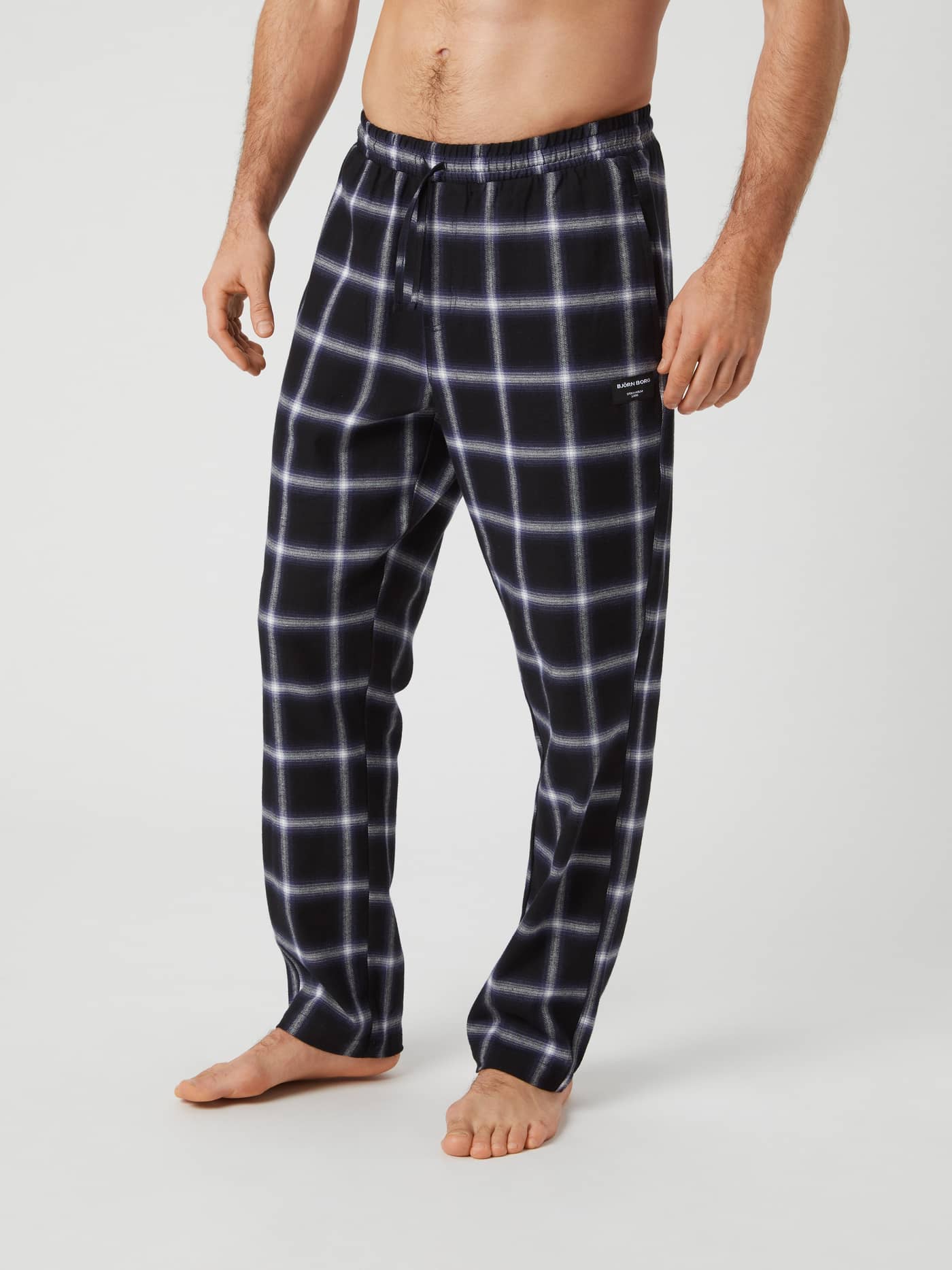 A man models the Björn Borg Core Flannel Pyjama Pants in a black and white lumber check pattern. - Image 2