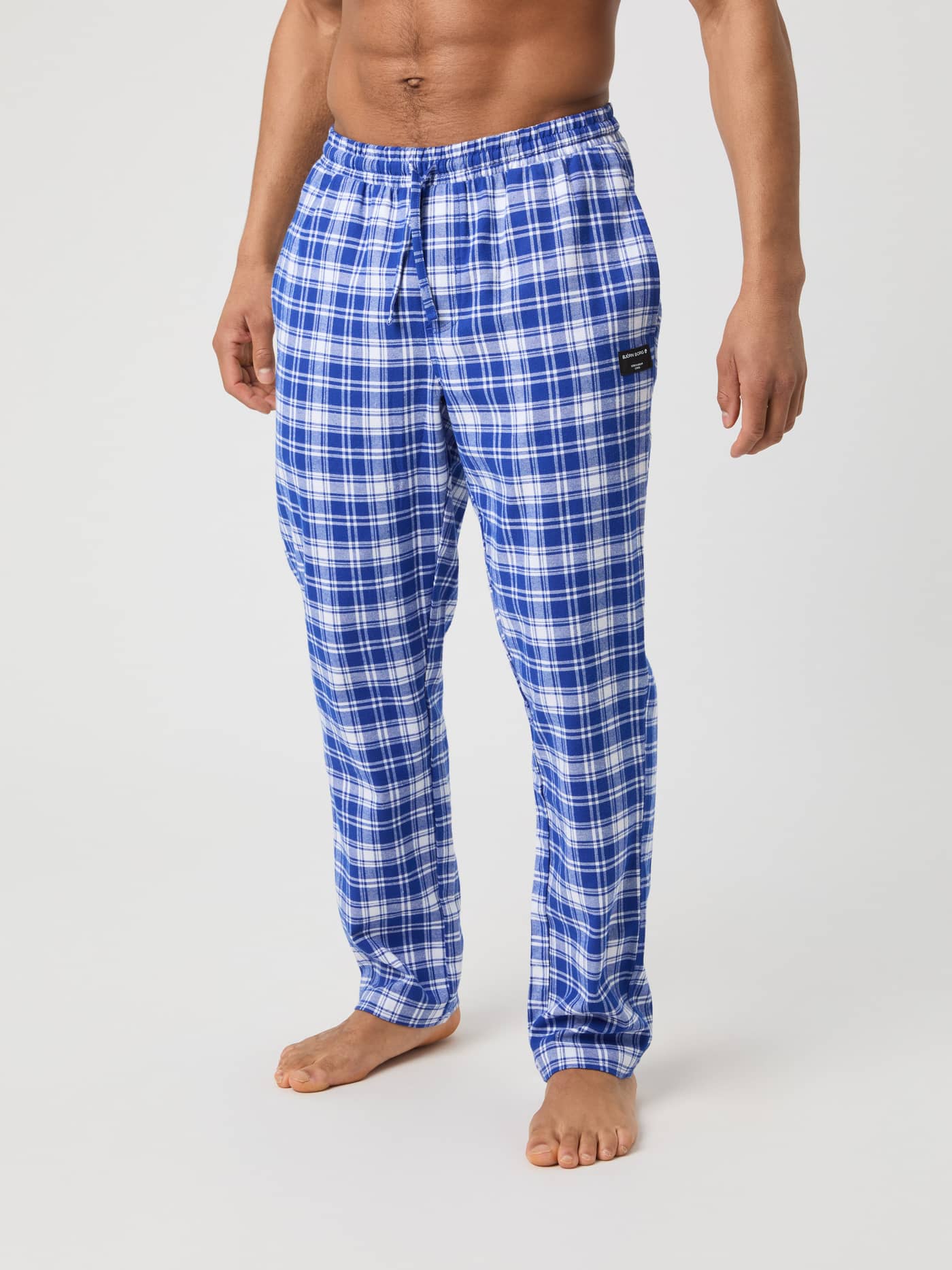 A male model seen from the front wearing Björn Borg Core Flannel Pyjama Pants in a blue and white check pattern. - Image 2