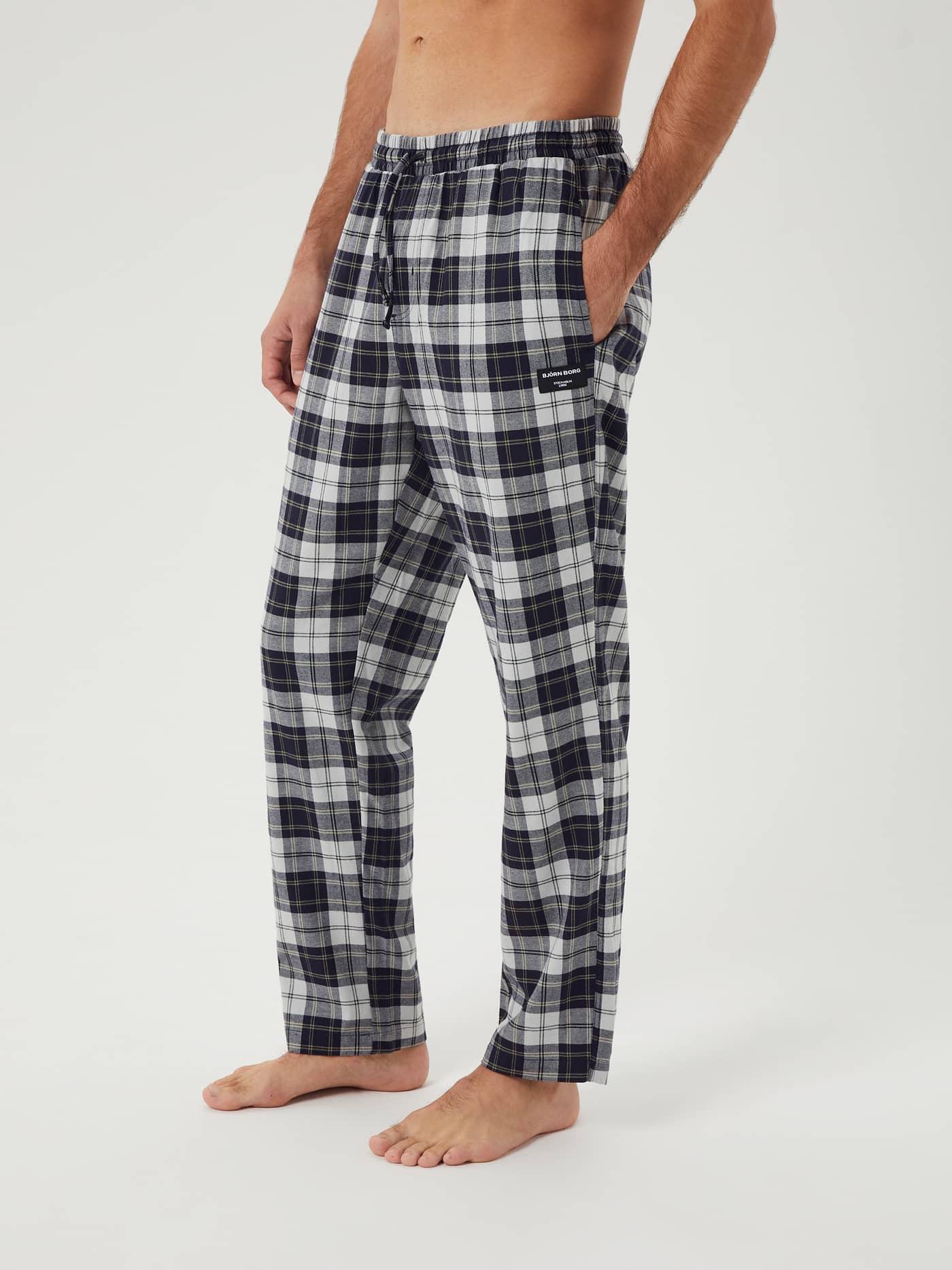 Man seen from the side wearing the Björn Borg Core Flannel Pyjama Pants in a dark navy and white tartan pattern. - Image 1
