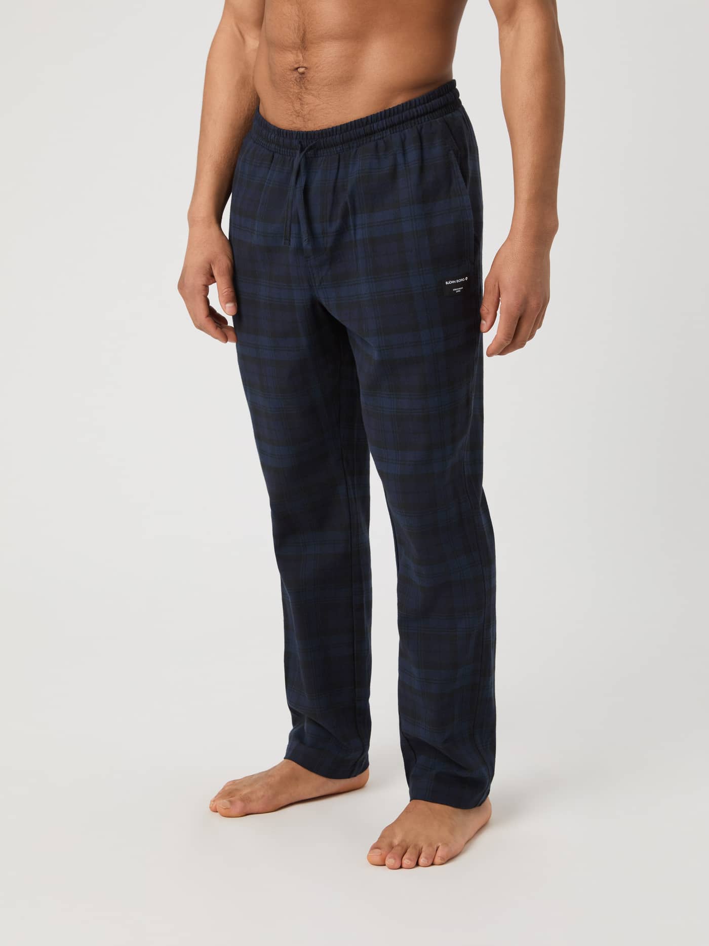 Side view of model wearing Björn Borg Core Flannel Pyjama Pants in navy and black classic tartan. - Image 2